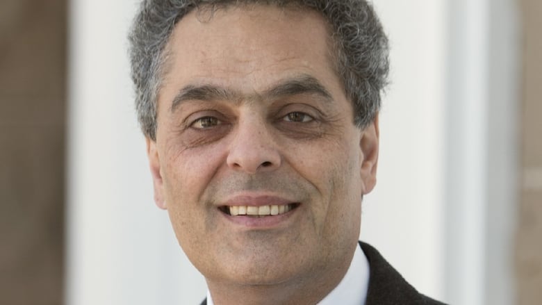 A man in a suit smiles.