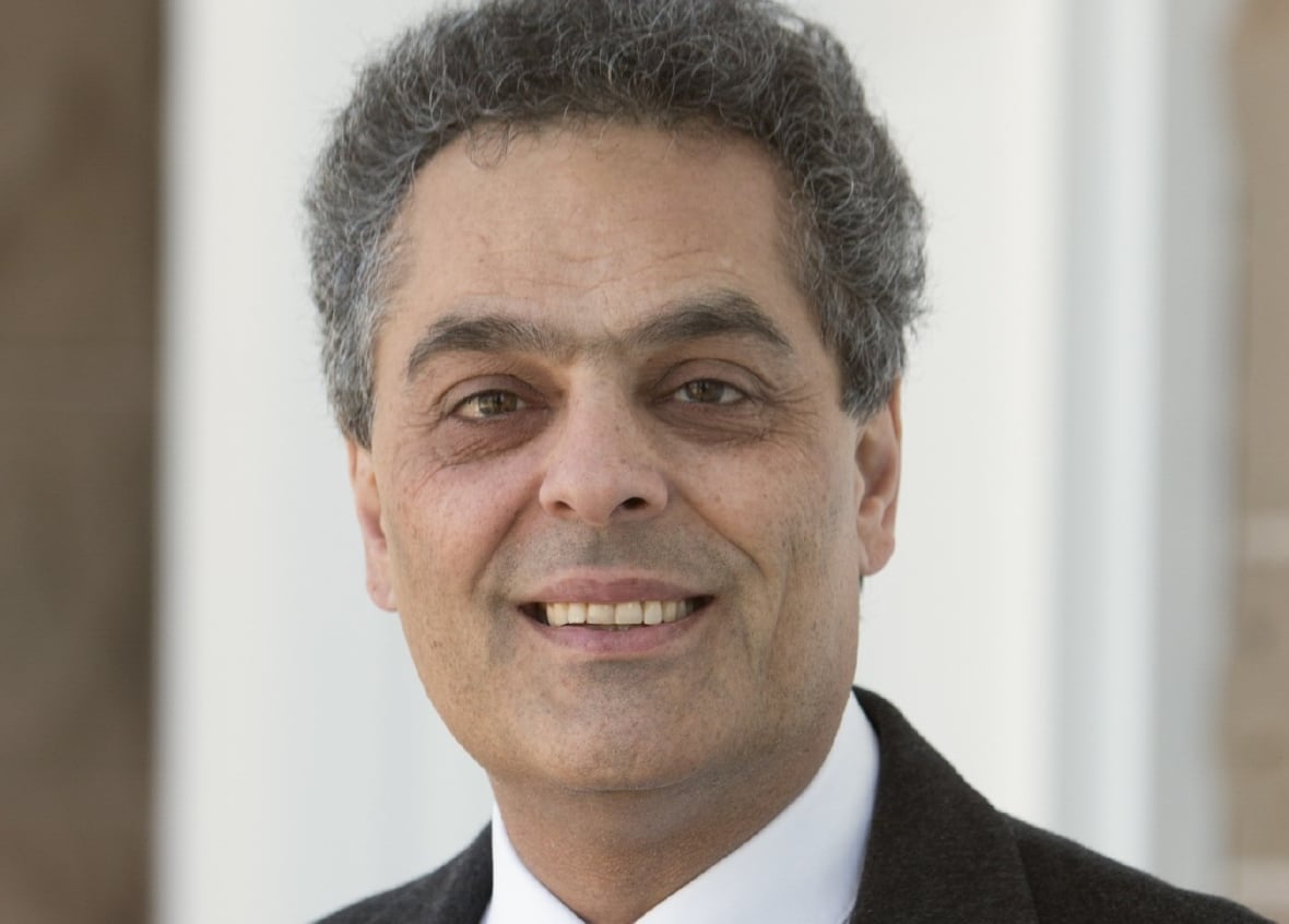 A man in a suit smiles.