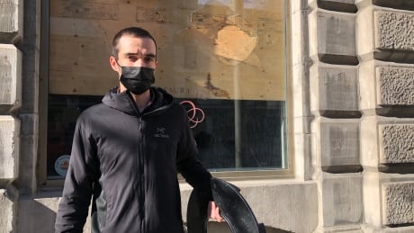 Daniel Loureiro, co-owner of Helena restaurant in Old Montreal, holds the trash can lid someone threw through the building's window Sunday night. Daniel Loureiro