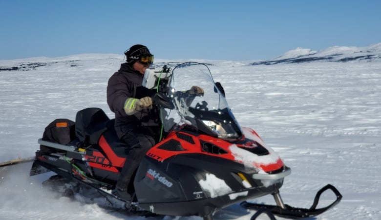 Rex Holwell sits on a snowmobile