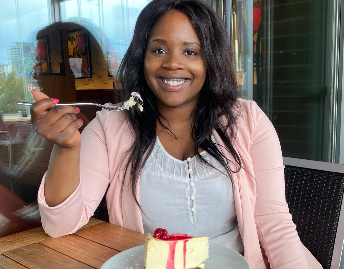 A woman sitting at a table eating a piece of cheesecake.
