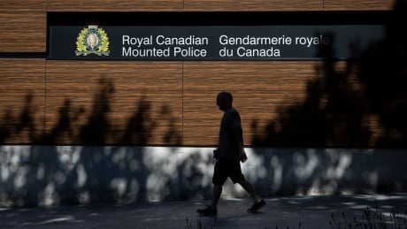 A man walks by a sign outside of the RCMP "E" Division headquarters in Surrey, British Columbia on Monday May 31, 2021. TRINA HUNT
