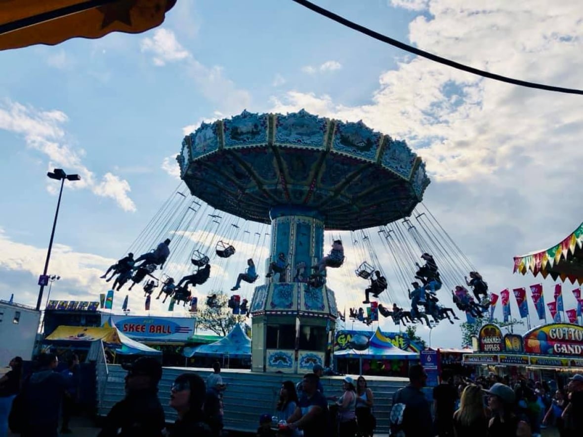 People sit in swings at a ride at a carnival.