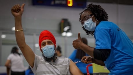 Kulwinder Singh is adminstered vaccine from Dr. Yvonne Kangong at a pop-up clinic in Calgary. Almost 69 per cent of eligible Albertans have now been vaccinated. vaccine covid ahs
