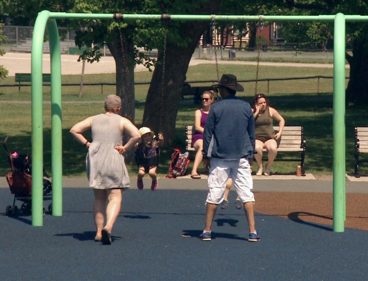 Parents pushing kids on park swings