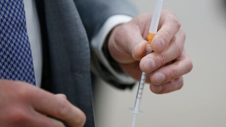 Dr. Brent Roussin, chief provincial public health officer, prepares the COVID-19 vaccination for Manitoba Premier Brian Pallister at the convention centre in Winnipeg, Thursday, April 8, 2021. COVID Mba 20210408