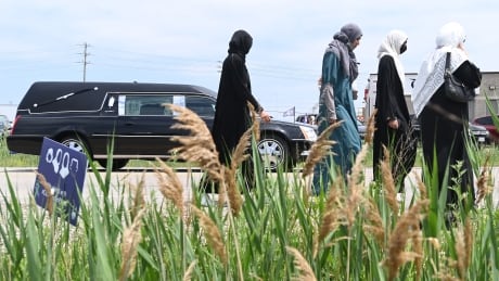 People walk beside a hearse as the procession arrives at the funeral for the four Muslim family members killed in a deadly vehicle attack, at the Islamic Centre of Southwest Ontario in London, Ont., on Saturday, June 12, 2021. Talat Afzaal, 74, her son Salman Afzaal, 46, his wife Madiha Salman, 44, and their 15-year-old daughter Yumna Salman all died last Sunday night while out for a walk after a man in a truck drove them down in what police have called a premeditated attack because they were Muslim. THE CANADIAN PRESS/Nathan Denette Ont London Attack 20210612