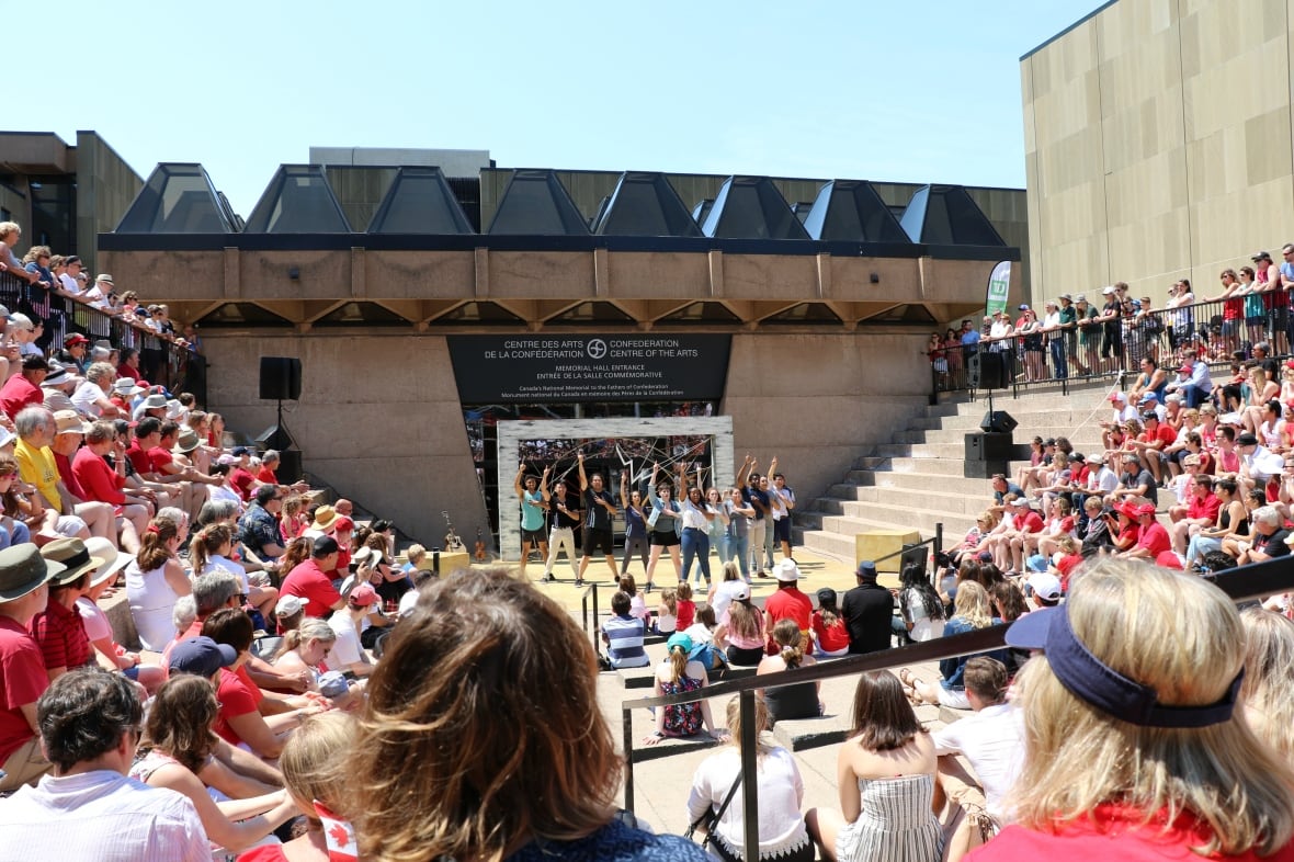 Many spectators sit and watch as a group performs at the Confederation Centre of the Arts outdoor area.