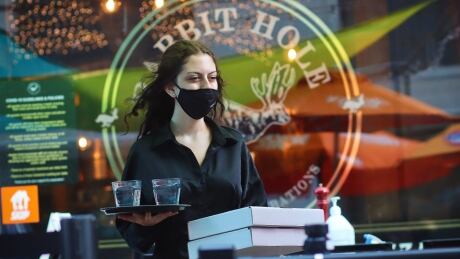 A server wears a mask while working at a Sparks Street restaurant in downtown Ottawa on July 10, 2021, during the COVID-19 pandemic. pandemic server covid-19 restaurant patio worker mask ottawa