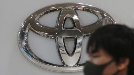 FILE - In this Nov. 2, 2020, file photo, visitor wearing a face mask to help curb the spread of the coronavirus walks by the logo of Toyota Motor Corp. at its showroom in Tokyo. Toyota won't be airing any Olympic-themed advertisements on Japanese TV during the Tokyo Games despite being one of the IOC's top corporate sponsors. The unusual decision by the country's top automaker underlines how polarizing the Games have become in Japan as COVID-19 infections rise ahead of the July 23, 2021, opening ceremony.(AP Photo/Koji Sasahara, File) Tokyo Olympics Toyota Ads
