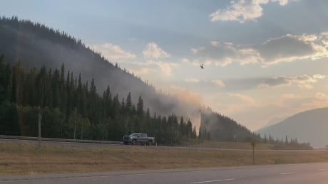 A helicopter drops water on a wildfire near Lac des Arcs, Alta., on July 23, 2021. Wildfire near Lac des Arcs