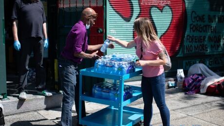 Water is handed out outside of an Overdose Prevention Site in Vancouver’s Downtown Eastside on Tuesday, July 27, 2021. (Maggie MacPherson/CBC) HEAT WAVE PLANS