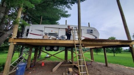 Tine Arthurs and her dog Buddy Love sit in their newly perched RV-Treehouse that she and her husband Paul have been building to avoid flood waters Tina Arthurs RV-Treehouse