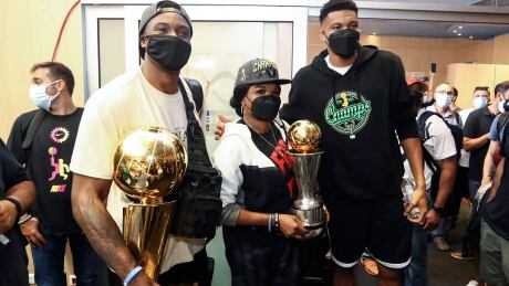 NBA champions and brothers Thanasis, left, and Giannis Antetokounmpo, right, have made good on a promise to take the championship trophy to Sepolia, the run-down Athens neighborhood where they grew up. They are pictured with their mother Veronica at the International Airport Eleftherios Venizelos in Greece. 1234375659