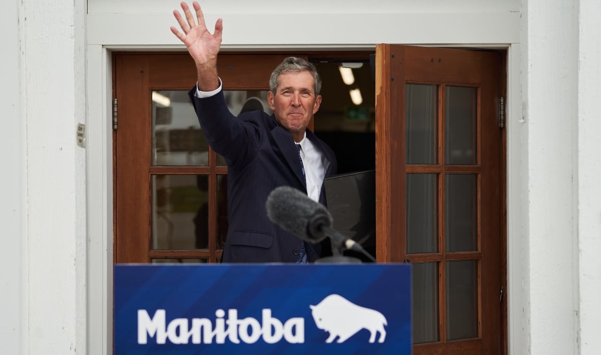 A man waves in front of a podium that says "Manitoba."