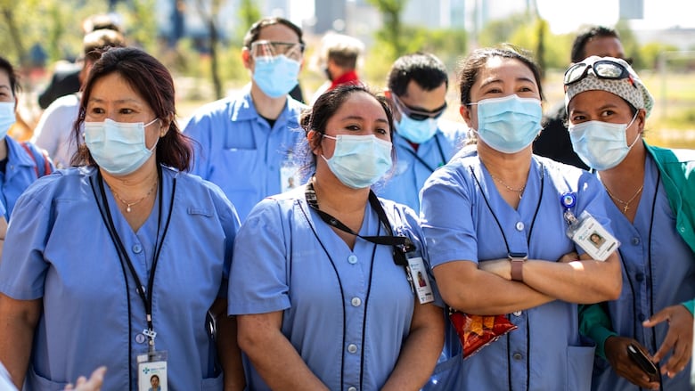 People in masks stand outside.