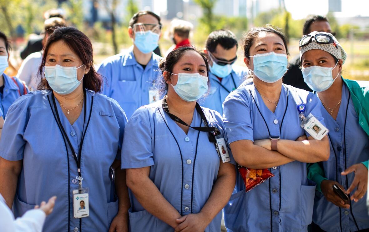 People in masks stand outside.