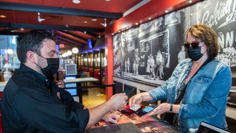 Jimmy Staveris, manager of Dunn's Famous restaurant scans the COVID-19 QR code of a client in Montreal, Wednesday, September 1, 2021, as the Quebec government's COVID-19 vaccine passport comes into effect. THE CANADIAN PRESS/Graham Hughes COVID Que vaccine passport 20210901