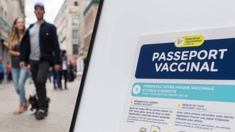 People walk by a sign outside a restaurant advising customers of the Quebec government’s newly implemented Covid-19 vaccine passport in Montreal, Monday, Sept. 6, 2021, as the COVID-19 pandemic continues in Canada and around the world. COVID Que 20210906