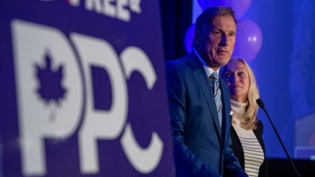 People's Party of Canada Leader Maxime Bernier, with his wife, Catherine Letarte, speaks from a podium to supporters during the PPC headquarters election night event in Saskatoon on Sept. 20, 2021. FedElxn PPC 20210920
