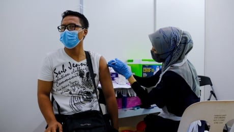 A health worker administers a dose of the Sinovac Biotech Covid-19 vaccine at a vaccination center set up at the PKNS Sports Complex in Kelana Jaya, Selangor, Malaysia, on Wednesday, Aug. 11, 2021. Malaysia has eased virus restrictions for those who have completed the full vaccination regime, allowing them to cross state borders and dine at restaurants as authorities seek to re-open the economy. Photographer: Samsul Said/Bloomberg Malaysia COVID vaccine