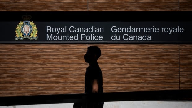 A man walks past a sign that reads 'Royal Canadian Mounted Police.'