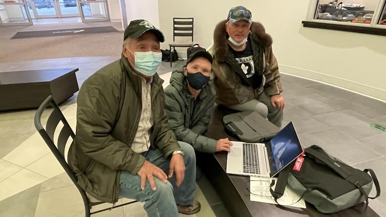 Three men in masks stare straight.