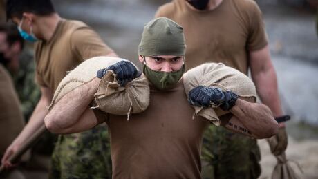 A member of the Canadian Forces slings sandbags while building a temporary dike behind houses on Clayburn Creek near Abbotsford, B.C. on Wednesday. The prime minister is set to visit the devastated city on Friday in his first visit since widespread floods and landslides struck B.C. nearly two weeks ago. APTOPIX Canada Mudslides