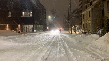 A person walks in the middle of a snow-covered street in downtown Halifax early Thursday morning. Snowstorm
