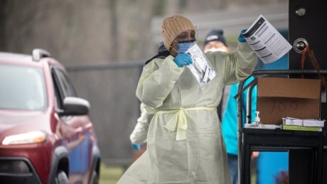 A health-care worker hands out COVID-19 rapid tests to people at the Bear Creek rapid test distribution centre in Surrey, B.C., on Jan. 18, 2022. RAPID TEST