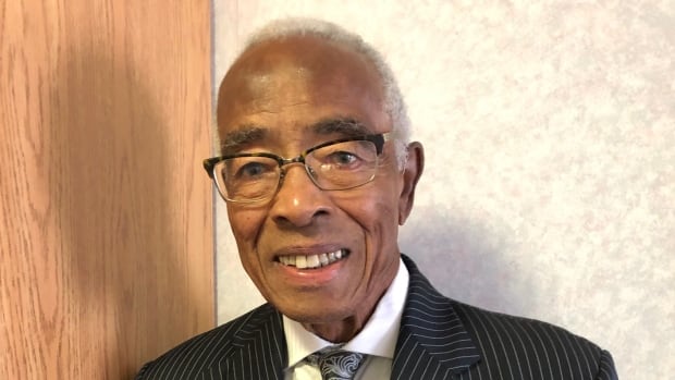An older Black man with grey hair wearing a pinstripe suit