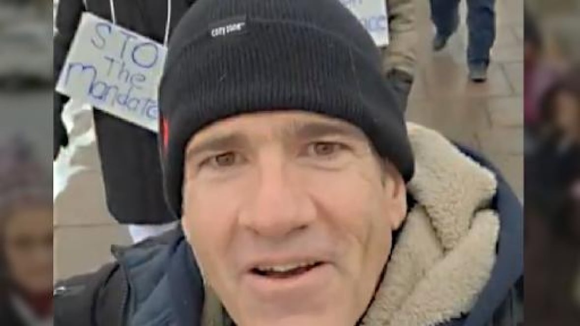 Un uomo con un cappello in piedi tra la folla all'esterno.