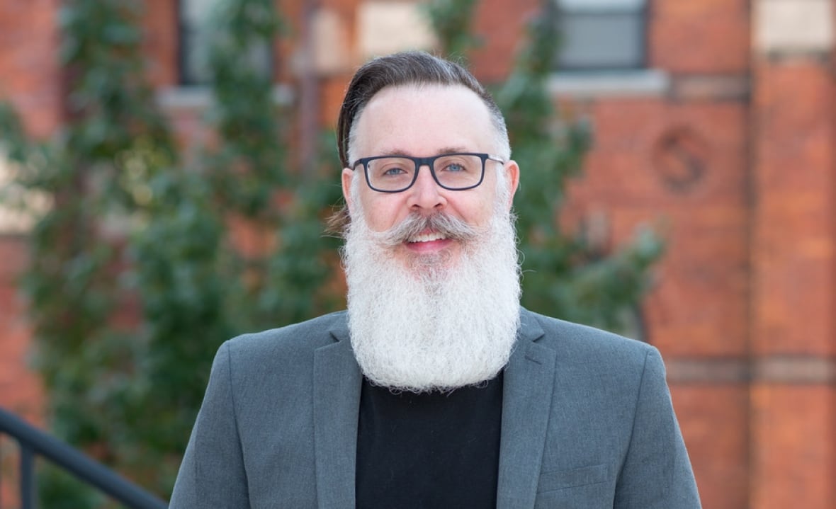A man with a big beard smiles.