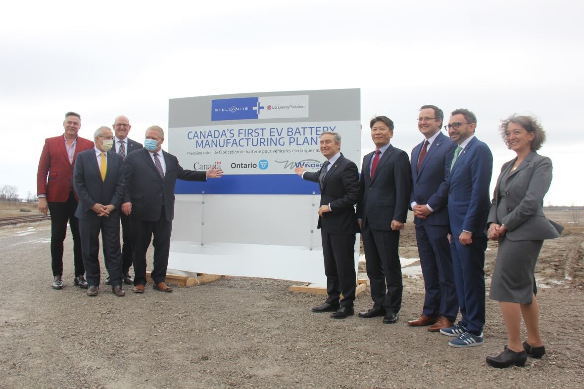Government officials stand next to a sign