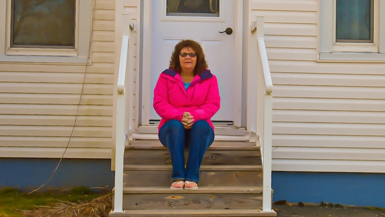 A woman sits on a front porch