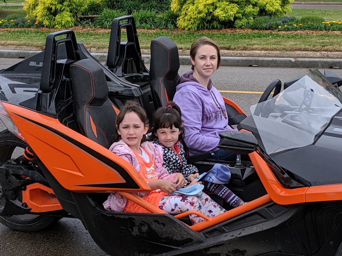Two girls and a woman sit in a Go Kart.