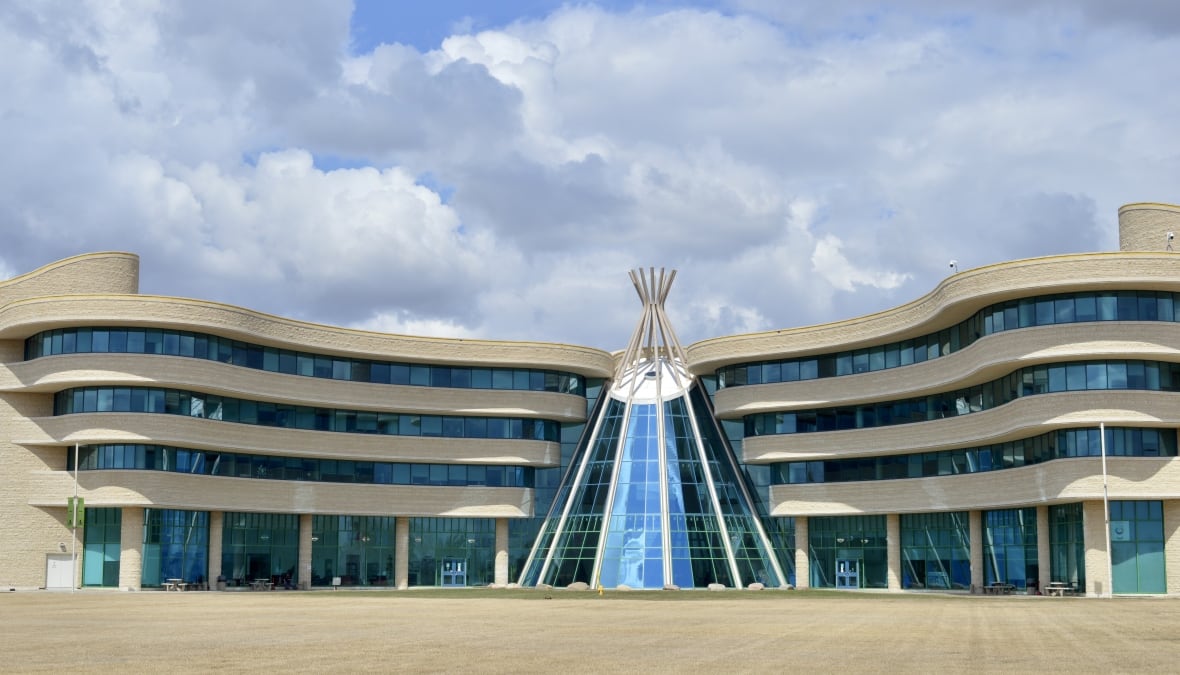 A sandstone building with flowing lines and a blue glass entryway in the shape of a teepee.
