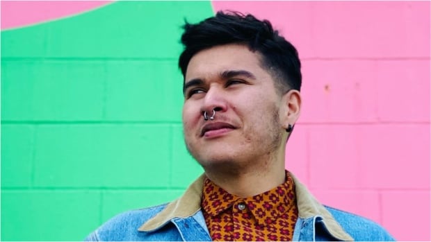 A man in a denim jacket looking past the camera into the distance.