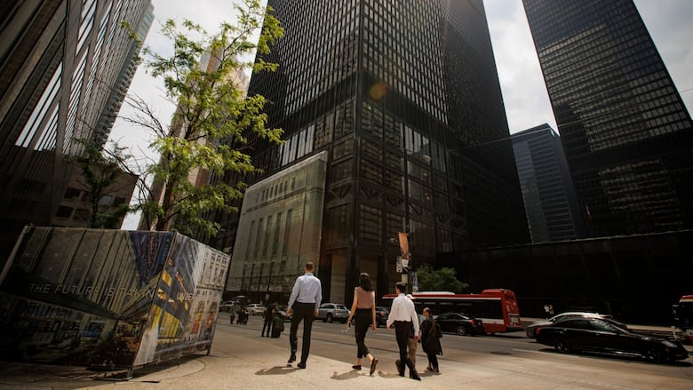 People walk near tall bank towers.