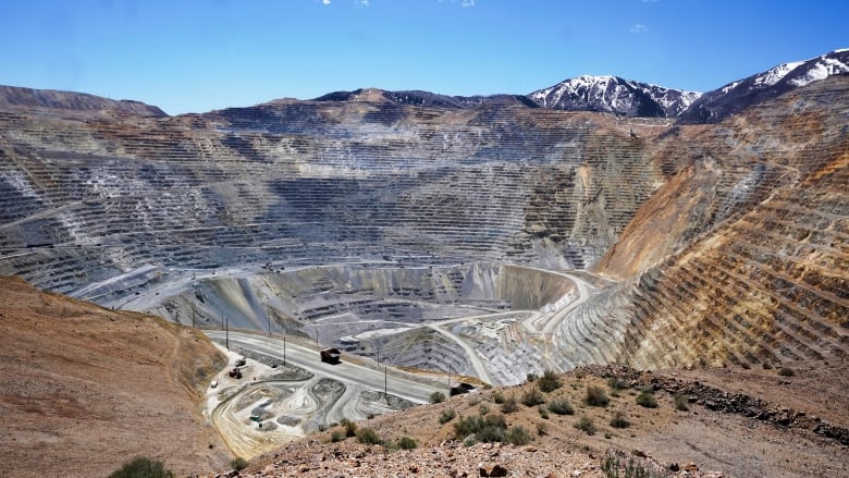 A large truck drives inside a massive open-pit mine. 