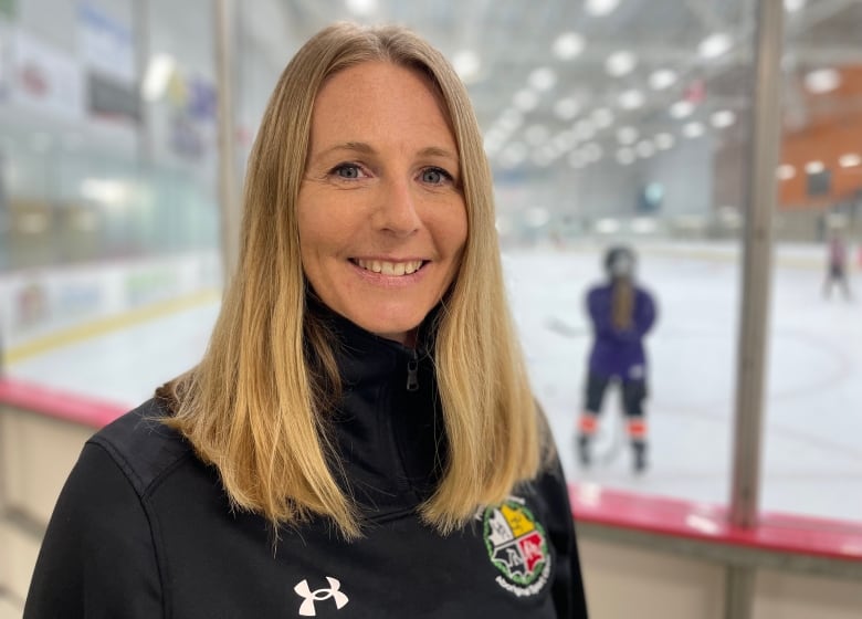 Blond woman smiles to camera inside a rink.