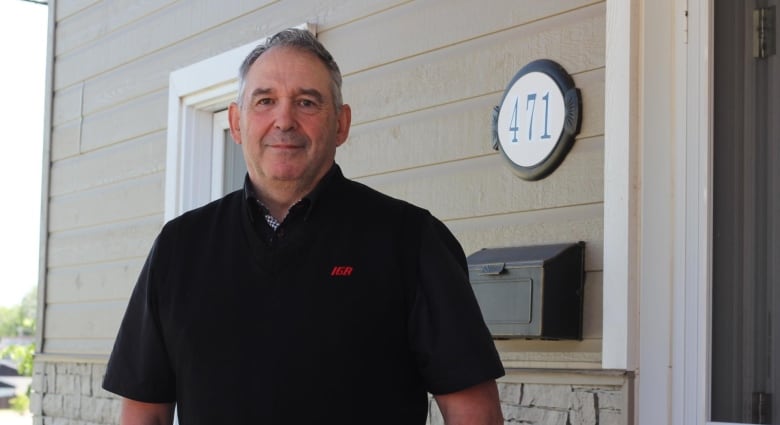 A Saguenay resident stands in front of his house.