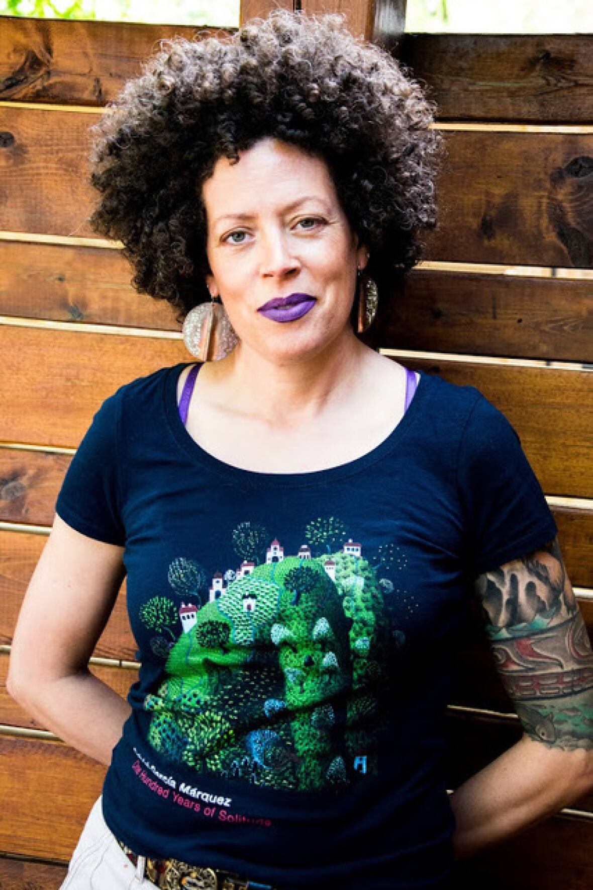 A portrait of a smiling woman with curly black hair and purple lipstick.