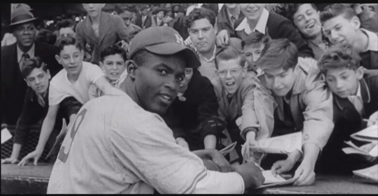 Jackie Robinson signing autographs for a group of young children.