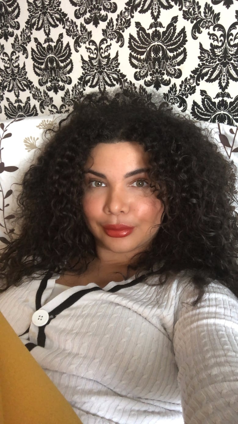 A woman with curly hair reclines in a bed. 