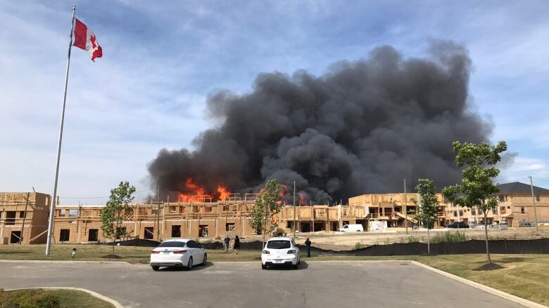 Homes in construction on fire with a big, cloud of black smoke.