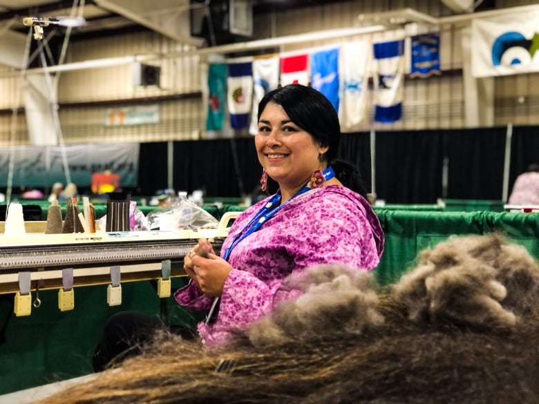 A woman smiles at the camera behind a pile of brown fibre.