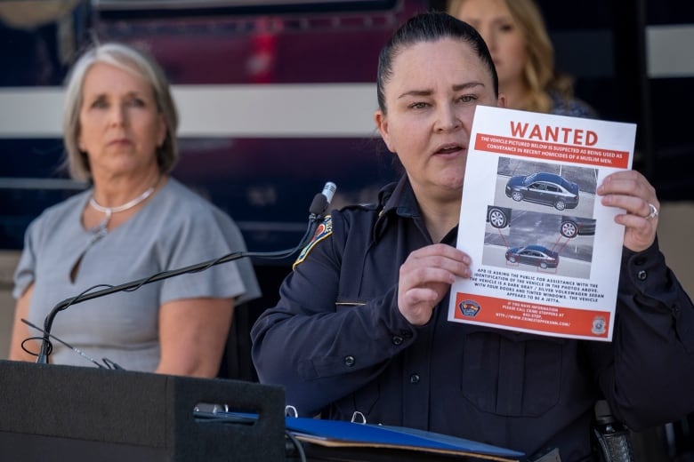 A woman holds up a piece of paper with photos of a car ad the word "Wanted."