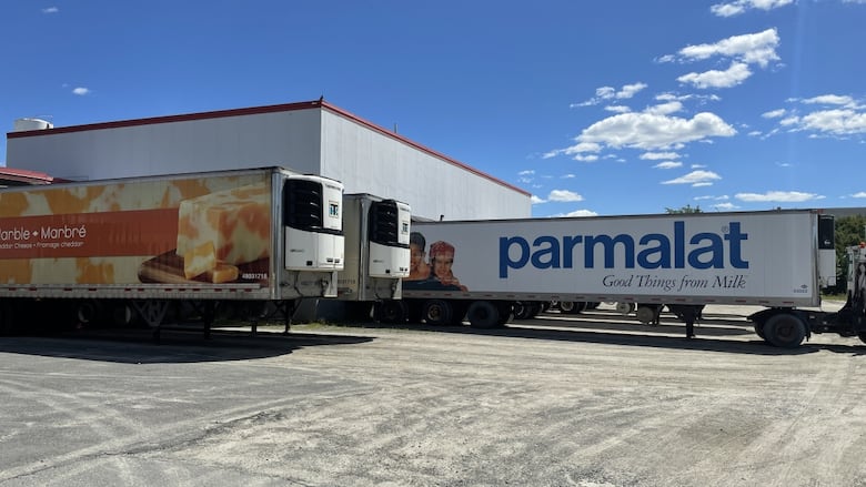 A large warehouse with some trailers nearby.