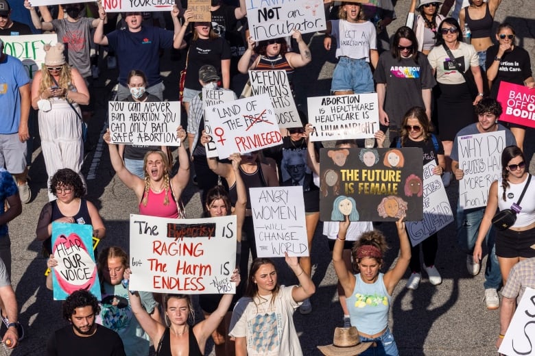 People hold up protest signs.